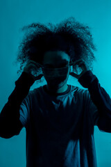 Future concept, silhouette with blue light with futuristic led glasses. Young man with afro hair on white background