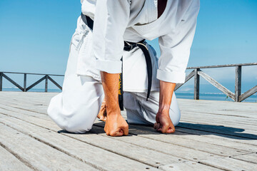 Karate man leaning with clenched fists on wooden platform