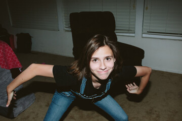 Teen girl in overalls poses silly and smirks at the camera