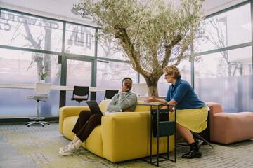 A full length photo of two multiracial colleagues having a conversation on a break