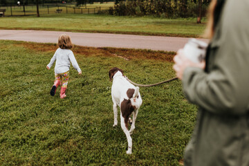 Family playfully walks dog outside during Fall on local walking trail