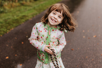Smiling girl missing tooth holds dog leash on local walking path