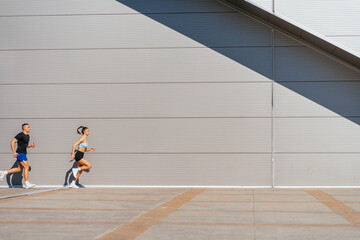 Full length photo of two athletes, a couple, running in a row together on a beautiful sunny day