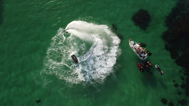 A man flies on a FlyBoard. Aerial top down view. Water extreme sport, azure summer sea with outdoors active people enjoying water sports. Flyboarding and seariding, Recreation and sports concepts.