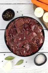 Raw chicken liver with vegetables and spices on a white wooden background. Top view. Noise to tail concept.