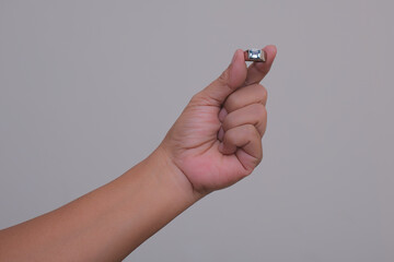 Hand showing a tiny ring with blue sapphire stone over white background