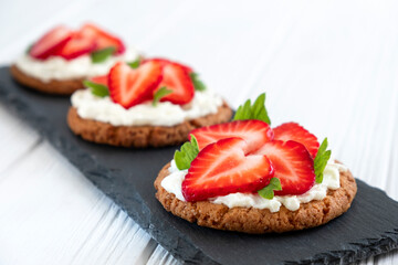 Healthy toast with strawberry, cream cheese and mint leaf. Tasty breakfast. Clean eating, dieting or recipe of healthy snack sandwich for vegetarian. Restaurant serving on slate board.