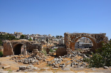 Sunny temples, arches, the Nymphaeum, stone ornaments, columns and column bases on the ruins of the city of Jerash in Jordan.