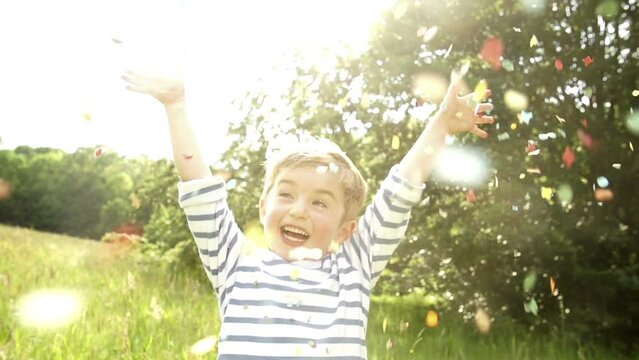Little boy throwing confetti in the park in slow motion