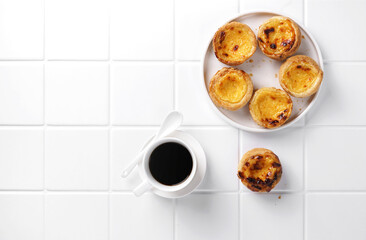 typical portuguese egg tart pastel de nata with cup of coffee on white background, top view, copy space - obrazy, fototapety, plakaty