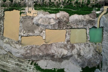 A top-down aerial view of several slurry wastewater pits at a concrete batching plant yard. They...