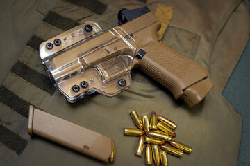 Compact 9mm pistol in sandy color with clear plastic holster and ammo.