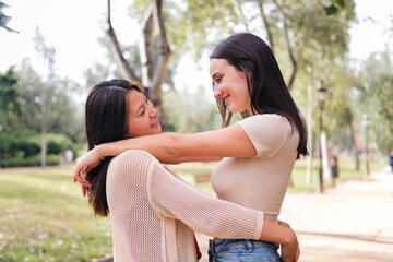 couple of young women embracing looking into eyes during a date in a park, concept of friendship and love between people of the same sex