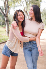 Fototapeta premium couple of happy women walk embracing and laughing during a date in a park, concept of friendship and love between people of the same sex