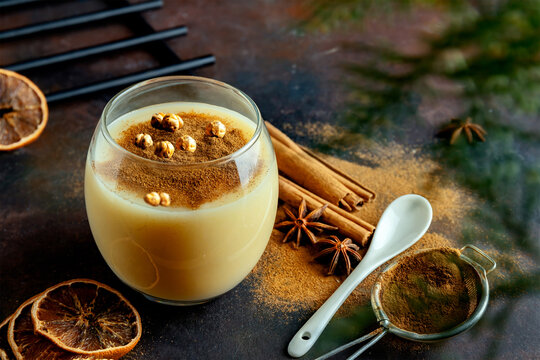 Traditional Turkish drink boza with cinnamon and roasted chickpea. Delicious winter beverage in glass cup. Selective focus. Blurred background.