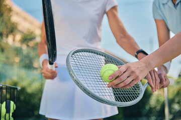 Tennis training, hands and ball with women and athlete on outdoor turf, instructor or coach, fitness motivation and help. Exercise, sports lesson and workout together, teaching and learn on court