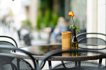 Outdoor restaurant table beautifully decorated with rose flower in a bottle in Vilnius, Lithuania, on nice summer day.