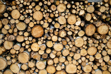 Background of dry chopped firewood logs stacked up on top of each other