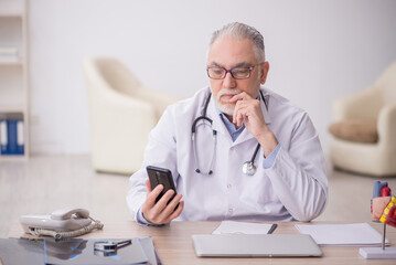 Old male doctor in telemedicine concept