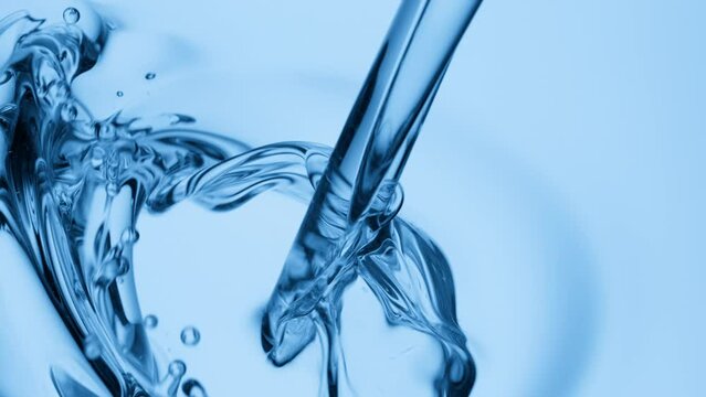 Crane shot of blue tansy oil is being poured into blue oil on blue background | Abstract skin care cosmetics ingredients formulating concept