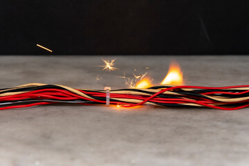 fire burns in twisted electric wires, sparks fly on a dark background. A short circuit in the...
