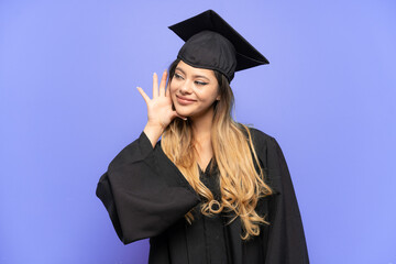 Young university graduate Russian girl isolated on white background listening to something by putting hand on the ear