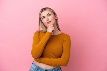 Young caucasian woman isolated on pink background having doubts