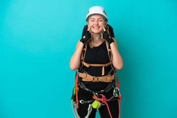 Young caucasian rock climber woman isolated on blue background smiling with a happy and pleasant expression