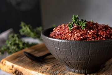 Homemade red wine infused salt in a black bowl. Condiment to aromatize and season food