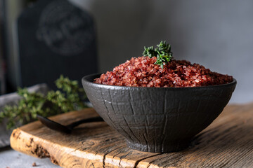 Homemade red wine infused salt in a black bowl. Condiment to aromatize and season food