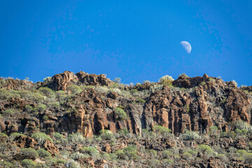 Day moon above mountains