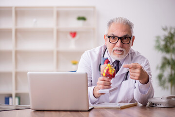 Old male doctor cardiologist working in the clinic