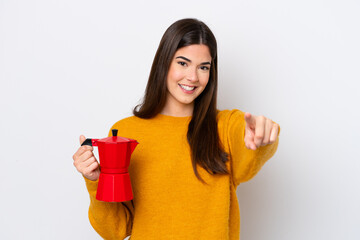 Young Brazilian woman holding coffee pot isolated on white background points finger at you with a confident expression