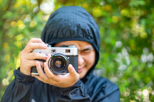 woman taking a picture with a camera, film camera in the hands of a girl taking a picture. Green trees bokeh background, woman taking a photo with a camera, selective focus, soft focus.