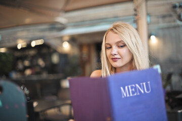young woman chooses dishes from the menu in the restaurant
