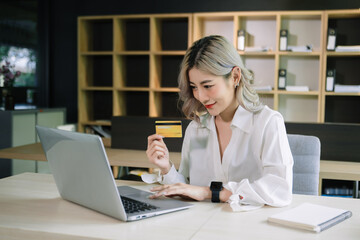 Woman using smart phone for mobile payments online shopping,omni channel,sitting on table,virtual icons graphics interface screen in morning light.