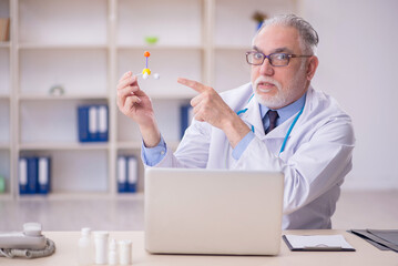 Old male doctor holding molecular model in the clinic