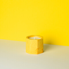 A candle in a candlestick made of acrylic material for home decor on a yellow-white background.