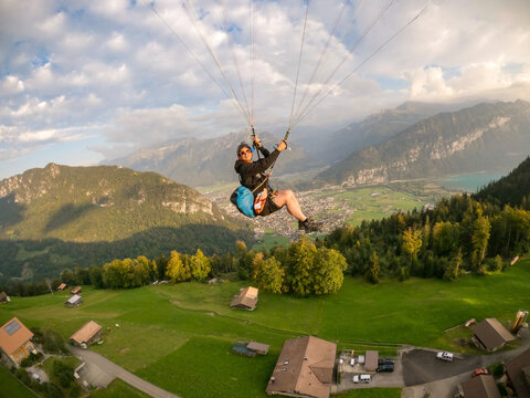 Paragliding pilot smiling flying over Swiss alps. Adventure concept