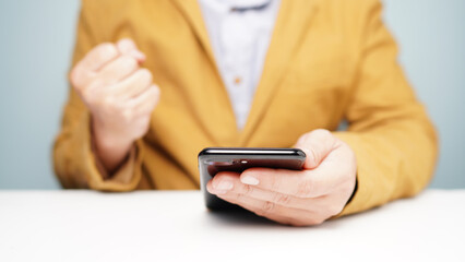 Cheerful man congratulating success clenched his fists. smartphone in hand
