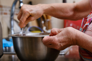 Detail of the hands of an elderly woman with arthritis cooking