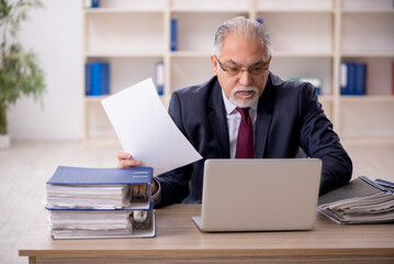 Old male employee sitting at workplace