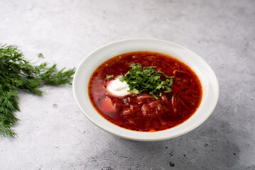 Red delicious delicious borscht in a white plate on a gray background