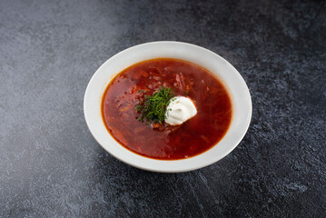 Red delicious delicious borscht in a white plate on a gray background