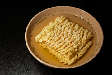 egg instant noodles are poured with water in a plate on a black background