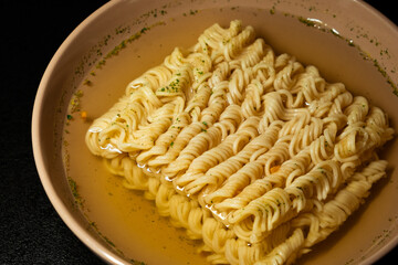 egg instant noodles are poured with water in a plate on a black background