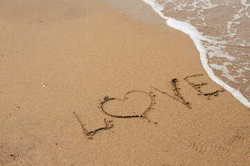 Love lettering on the sandy beach and sea water