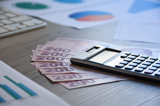 Financial concepts, a calculator on the turkish currency with business graphs on the office desk
