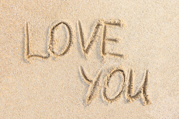 Love You words written on sand. Beach and sunny textured background