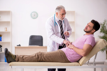 Obraz premium Young male patient visiting old male doctor